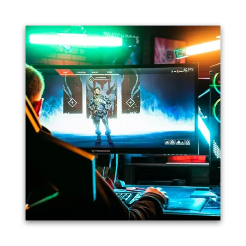Person seated at a gaming desk with a monitor showing a character in a video game.
