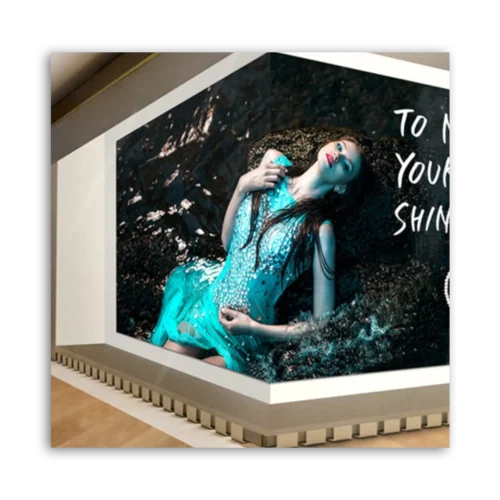 Model wearing a blue dress lying on a dark surface with text on the wall behind her.
