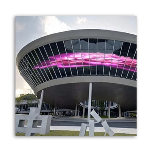 A modern building featuring a curved structure and large glass windows with a digital display.