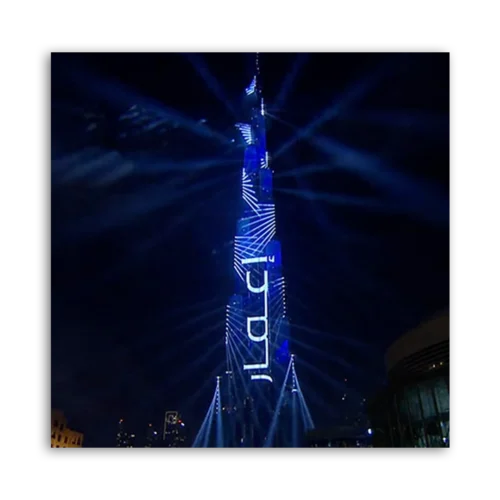 Burj Khalifa illuminated with blue lights and patterns during a light show at night.